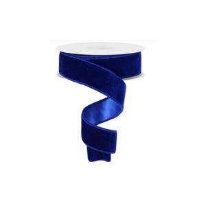 May include: A roll of royal blue velvet ribbon with a satin backing. The ribbon is unspooled, revealing its rich color and texture. This ribbon is suitable for crafts, gift wrapping, and decorative purposes.