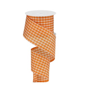 May include: A spool of orange and white gingham ribbon. The ribbon is tightly wound around a white cardboard core. The ribbon is unwound in a spiral, revealing the pattern. The ribbon is made of a fabric material.
