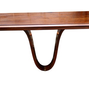 May include: A dark brown wooden console table with a curved, U-shaped base. The table top is rectangular and has a smooth, polished finish.