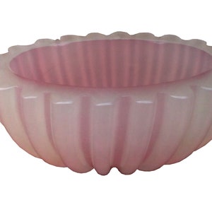 以下が含まれることがあります： フリルデザインのピンクのガラスボウル。ボウルは不透明なガラス製で、滑らかで丸みを帯びた形をしています。