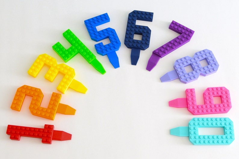 May include: A set of ten colorful plastic number candles, each shaped like a number from one to ten. The candles are arranged in a semi-circle on a white background. The candles are made to look like Lego bricks.