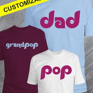 May include: Three customizable t-shirts. One is maroon with "grandpop" in light blue. Another is light blue with "dad" in magenta. The third is white with "pop" in magenta. A yellow banner at the top says "CUSTOMIZABLE".