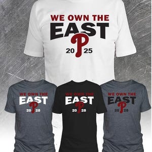 May include: A collection of t-shirts in white, black, and gray. Each shirt features the text "WE OWN THE EAST" in red and black, with the letter "P" and the numbers "20 25" in red. The shirts are short-sleeved.