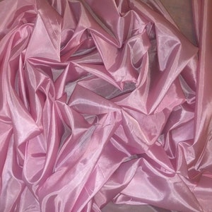 May include: Pink sheer fabric with a silky texture. The fabric is draped and folded, creating a soft and flowing look.
