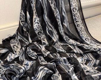 May include: A lightweight fabric featuring a repeating pattern of vertical black stripes alternating with silver and black leopard print bands. The material has a semi-sheer, flowing texture with a subtle sheen, creating a draped effect.