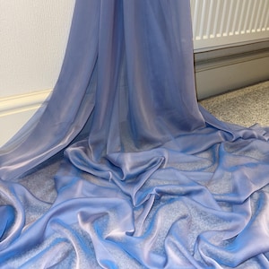 May include: A cascade of light blue fabric, shimmering with a delicate sheen. The material falls in soft, flowing folds, creating a sense of movement. The fabric's texture suggests a lightweight material, suitable for dresses or decorative applications.