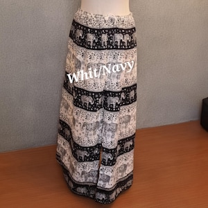 May include: Wide-leg pants featuring a repeating pattern of elephants and floral motifs in white and navy blue. The garment has an elasticized waistband with a drawstring and a vertical slit detail on the front. The text Whit/Navy is visible.
