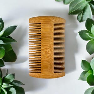 May include: A wooden comb with a natural finish. The comb has two rows of teeth and a rounded handle.