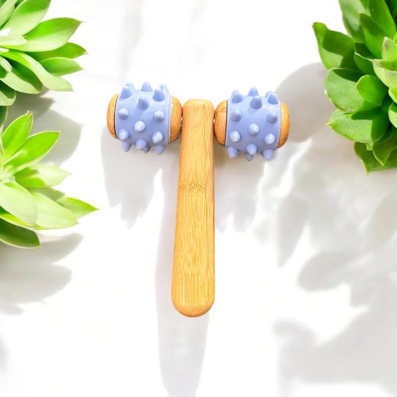 May include: A wooden face roller with two lavender-coloured spiked rollers. The roller is made of natural bamboo and has a smooth, polished finish.