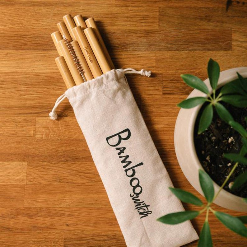K&ouml;nnte beinhalten: Ein Satz wiederverwendbarer Bambusstrohhalme in einer wei&szlig;en Stofftasche mit dem aufgedruckten Text "Bambooswitch". Die Strohhalme sind geb&uuml;ndelt und beinhalten eine Reinigungsb&uuml;rste.