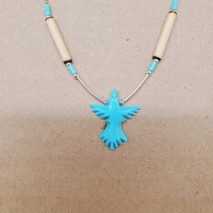 May include: A turquoise blue bird pendant necklace with a silver chain and wooden beads.