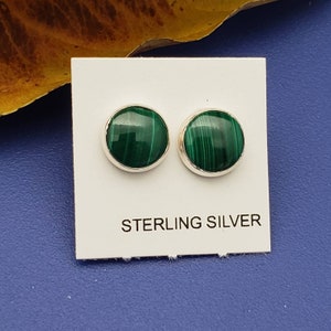 May include: A pair of sterling silver earrings with green malachite stones. The earrings are round and have a smooth finish.