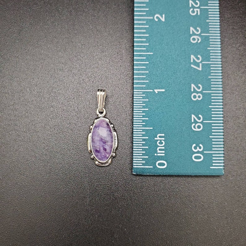Peut inclure: Un pendentif en argent avec une pierre ovale de couleur violette et blanche. Le pendentif mesure environ 2,5 cm de long.
