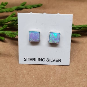 May include: A pair of sterling silver square stud earrings with iridescent opal stones.