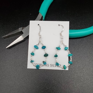 May include: Sterling silver earrings with turquoise stones in a teardrop shape.