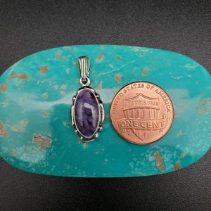 Peut inclure: Un pendentif en argent avec une pierre d'am&eacute;thyste violette sertie dans un cadre ovale en argent. Le pendentif est &agrave; peu pr&egrave;s de la taille d'une pi&egrave;ce de monnaie d'un centime d'euro.