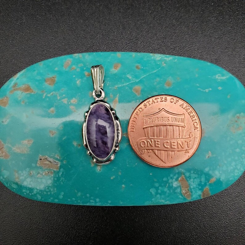 Peut inclure: Un pendentif en argent avec une pierre d'am&eacute;thyste violette sertie dans un cadre ovale en argent. Le pendentif est &agrave; peu pr&egrave;s de la taille d'une pi&egrave;ce de monnaie d'un centime d'euro.