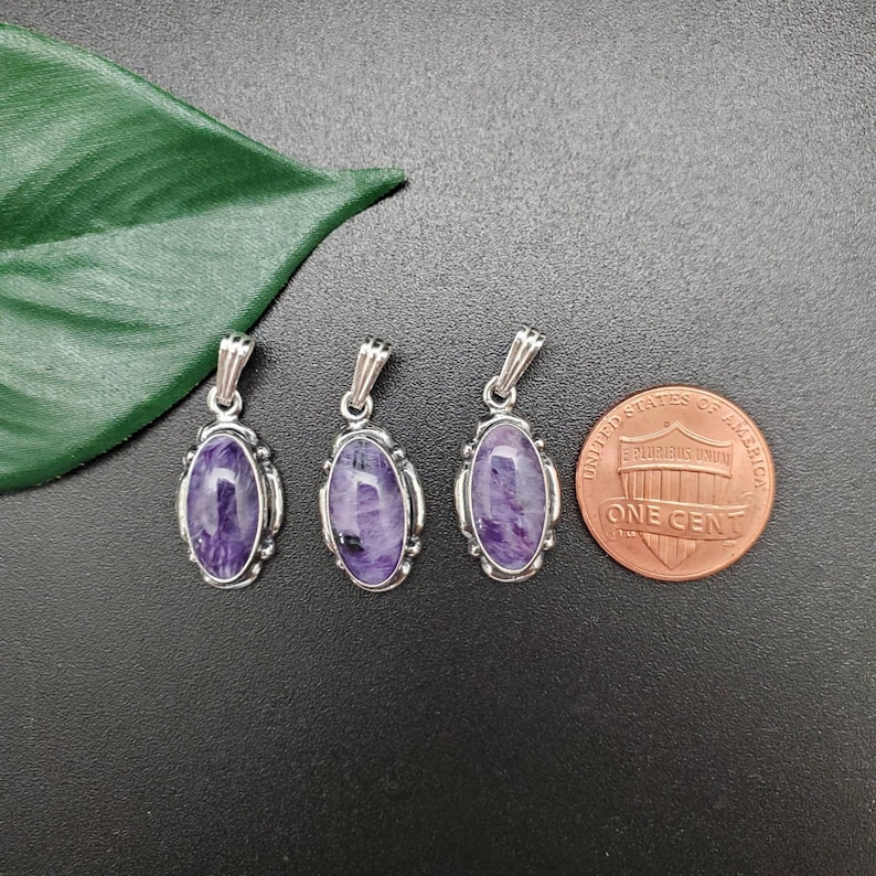 Peut inclure: Trois pendentifs en argent avec des pierres ovales de couleur violette et noire serties dans une b&eacute;li&egrave;re en argent. Les pendentifs sont &agrave; peu pr&egrave;s de la taille d'une pi&egrave;ce de monnaie fran&ccedil;aise.