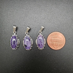 Peut inclure: Trois pendentifs en argent avec des pierres ovales violettes. Les pendentifs sont &agrave; peu pr&egrave;s de la taille d'une pi&egrave;ce de un centime d'euro.