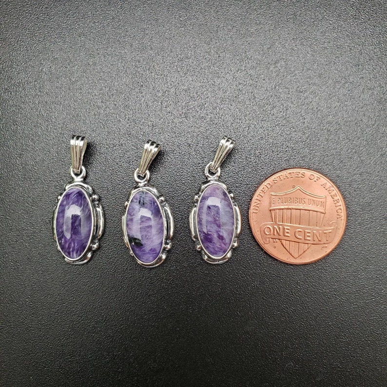 Peut inclure: Trois pendentifs en argent avec des pierres ovales violettes. Les pendentifs sont &agrave; peu pr&egrave;s de la taille d'une pi&egrave;ce de un centime d'euro.