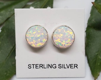 May include: A pair of sterling silver stud earrings with white opal stones. The earrings are on a white card with the text "STERLING SILVER".