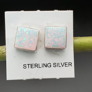 May include: A pair of square-shaped opal earrings with a silver setting. The earrings are on a white card with the text "STERLING SILVER".