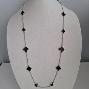 Långt silverhalsband, svart emaljklöver. 86 cm långt, rodiumpläterat.
