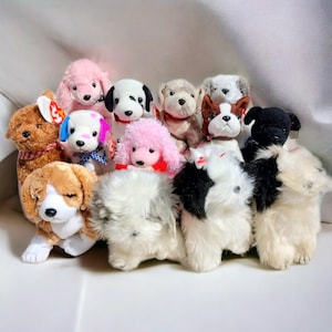 May include: A collection of 12 plush dog toys in various breeds and colours, including pink, white, brown, black, and grey. The toys are all in a sitting position and have a variety of facial expressions.