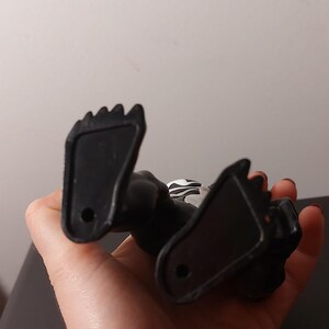 Peut inclure: Une figurine d'action en plastique noir avec un symbole blanc sur la poitrine. La figurine est couch&eacute;e sur le dos, les pieds en l'air.