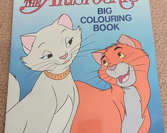 May include: A Disney "The Aristocats" big coloring book. The cover features illustrations of two cartoon cats, one white and one orange, with the title in red and the Disney logo. The Ladybird logo is in the bottom left corner.