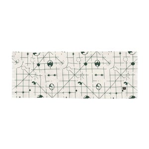 Op de afbeelding: Crèmekleurige sjaal met een herhalend donkergroen patroon van geometrische vormen, cirkels en gestileerde globe-achtige ontwerpen. De sjaal heeft een gefranjerde rand en een rechthoekige vorm. Het ontwerp is modern en abstract.