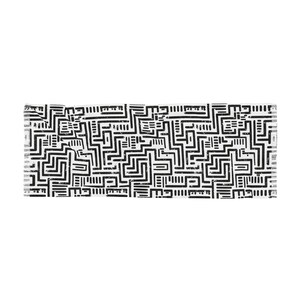 May include: A rectangular, white textile with a repeating black geometric pattern. The design features a maze-like arrangement of thick, black lines, creating a bold, abstract visual. The edges of the textile have a fringed detail.