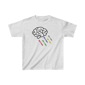 Könnte beinhalten: Ein weißes T-Shirt mit einer schwarzen Umrandung eines Gehirns und fünf bunten Buntstiften, die daraus fallen.