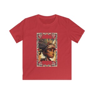 May include: Red t-shirt with a framed illustration of a person wearing a Native American headdress. The illustration has a detailed design with warm colours and a geometric border. The shirt is made of a soft material.