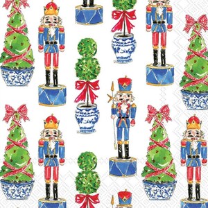May include: A white background with a repeating pattern of nutcrackers, Christmas trees, and topiaries. The nutcrackers are wearing blue and red uniforms with gold accents. The Christmas trees are decorated with red and white ribbons. The topiaries are in blue and white pots with red bows.