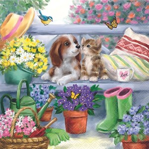 May include: A brown and white dog and a tabby cat sit on a blue bench with a red and white striped pillow and a green mug with the word "love" on it.  The bench is surrounded by flowers and gardening tools.