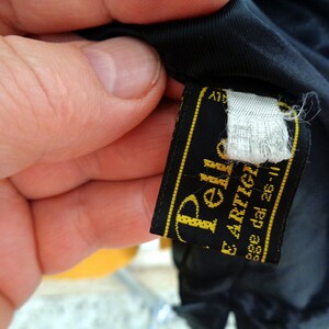 May include: Black leather label with gold stitching and the text "Pelle E. Artigiano" and "asse dal 26-II".