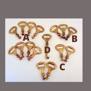 May include: A collection of vintage brass bottle openers arranged on a white surface. The openers have a key-like design with a loop handle and a bottle cap opener. The image is labeled with the letters A, B, C, and D.