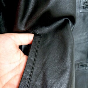 May include: Close-up of a black leather jacket with a zippered pocket and a seam down the side.