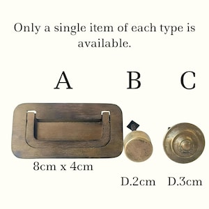 May include: Three antique brass hardware pieces: a rectangular pull (8cm x 4cm), a cylindrical knob (D.2cm), and a round knob (D.3cm). The text "Only a single item of each type is available" is above the hardware.