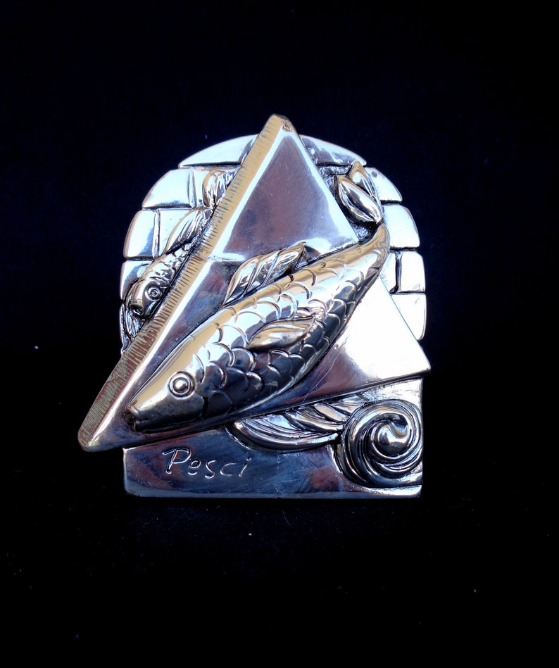 May include: Silver zodiac charm featuring two fish swimming in a triangle shape with the word "Pesci" inscribed below.