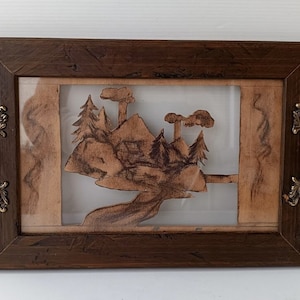 May include: A wooden landscape art piece featuring a mountain scene with trees and a river, framed in a dark brown wooden frame with ornate brass handles. The artwork is a unique decorative item.