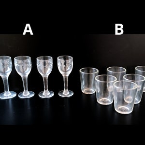 May include: Clear glass drinkware set. Four stemmed glasses with etched floral designs and six small, straight-sided glasses are arranged on a black surface. The glasses are empty and appear to be for serving beverages.