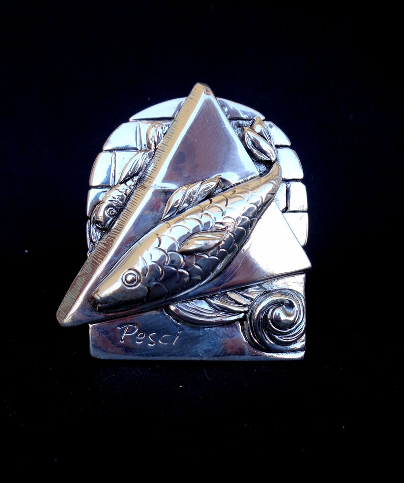 May include: Silver zodiac charm featuring two fish swimming in a triangle shape with the word "Pesci" inscribed below.