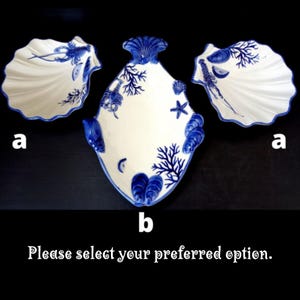 Op de afbeelding: Witte keramische serveerschalen met blauwe schelp- en koraalontwerpen. De set bevat twee schelpvormige schalen en een ruitvormige schaal. De tekst onderaan luidt: "Selecteer uw gewenste optie."