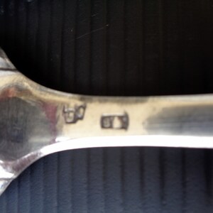 May include: Close-up of the back of a silver spoon with the markings "830" and "815" stamped on the back.