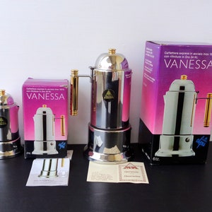 May include: Three silver and gold stovetop espresso makers with the brand name "alpu" on the side. The largest maker is 6 oz, the middle maker is 2 oz, and the smallest maker is 1 oz. The makers are on a black surface with a white background.