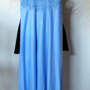 May include: A light blue slip dress with delicate lace trim around the neckline and straps. The dress has a flowing, silky fabric.
