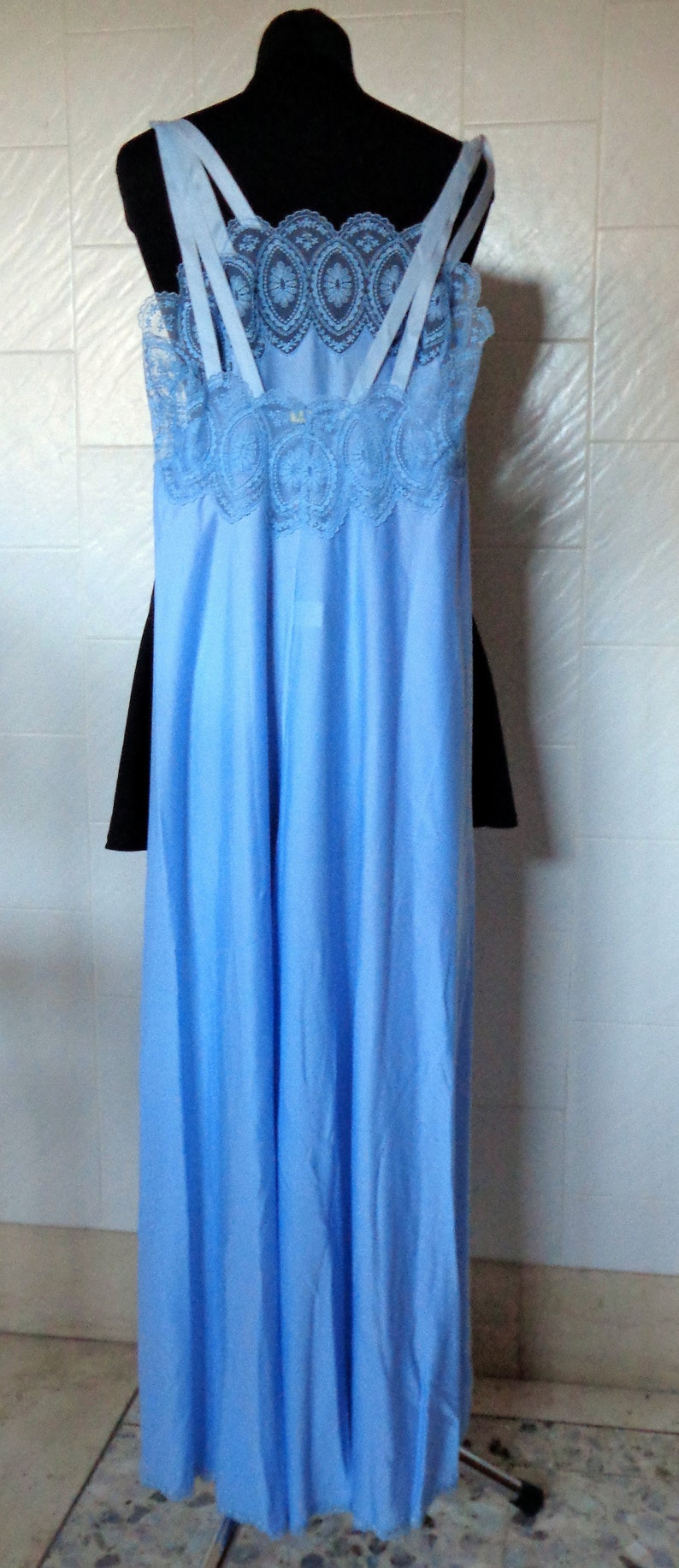 May include: A light blue slip dress with delicate lace trim around the neckline and straps. The dress has a flowing, silky fabric.