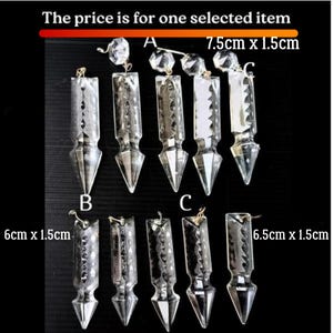 以下が含まれることがあります： さまざまな形とサイズの透明なクリスタルシャンデリアペンダント。画像には、7.5cm x 1.5cm、6cm x 1.5cm、6.5cm x 1.5cmの寸法の装飾的なクリスタルペンダントがいくつか表示されています。テキストは「価格は選択されたアイテム1つです」と書かれています。